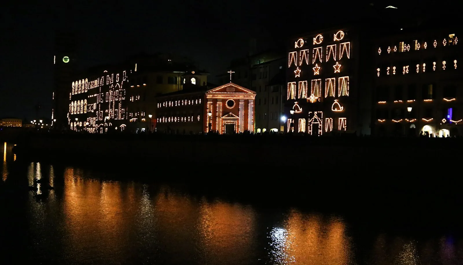 La Luminara di San Ranieri a Pisa: di notte i palazzi e una piccola chiesa sul Lungarno sono disegnati da migliaia di lumini che si riflettono nell’Arno